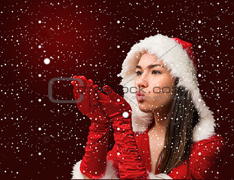 Composite image of pretty brunette in santa outfit blowing over hands