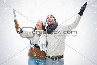 Composite image of attractive young couple in warm clothes with arms up