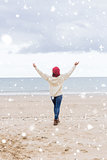 Composite image of woman in casual warm wear stretching arms on beach