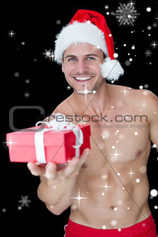 Composite image of smiling muscular man posing in sexy santa outfit offering gift