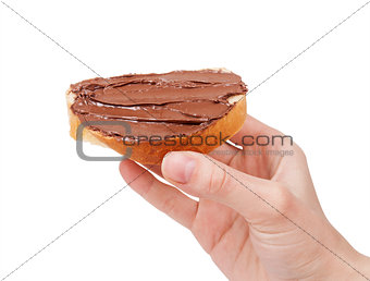 baguette slice spread with nut-choco paste in man hand, isolated on white