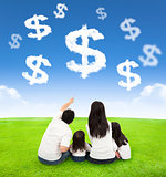 family sitting on a meadow with money of clouds