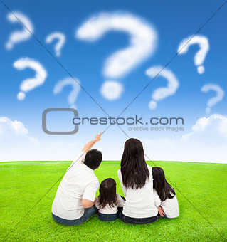 happy family sitting on a meadow with query of clouds