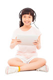 smiling little girl stiiting and holding a tablet with earphone