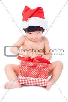 curious  baby in Santa cap looking at giftbox