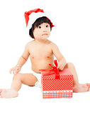adorable baby in Santa cap sitting on floor with christmas gift