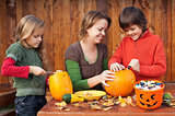 Woman helping kids to carve their Halloween jack-o-lantern