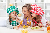 Woman and little girls preparing a fruit salad