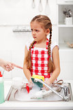 Sulking little girl doing the dishes
