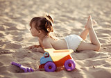Adorable baby girl lying in the sand on the beach
