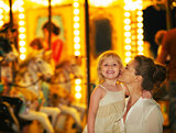 Portrait of happy mother and baby girl in front of carousel