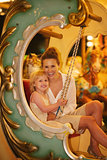 Portrait of happy mother and baby girl riding on carousel