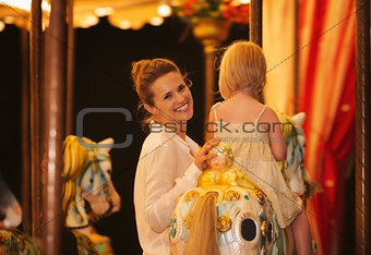 Mother and baby girl riding on carousel