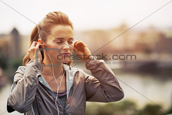 Portrait of fitness young woman wearing earphones in city in the