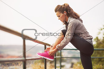 Fitness young woman tying shoelaces outdoors