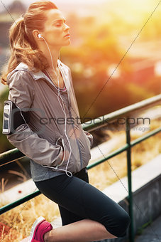 Portrait of relaxed fitness young woman in city in the evening