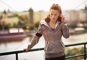 Fitness young woman in earphones in city in the evening