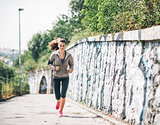 Full length portrait of fitness young woman jogging in the city 