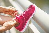 Closeup on fitness young woman tying shoelaces outdoors