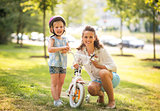 Portrait of happy mother and baby girl with bicycle