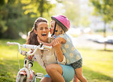 Happy mother and baby girl having fun in park with bicycle