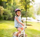 Portrait of displeased baby girl with bicycle in park