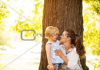 Portrait of happy mother and baby girl standing near tree