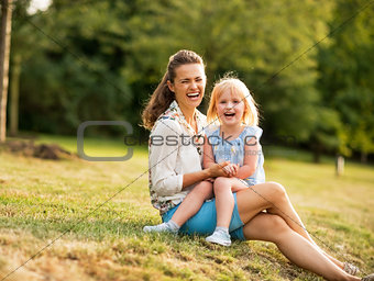 Portrait of happy mother and baby girl sitting outdoors