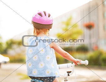 Baby girl riding bicycle. rear view
