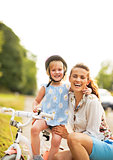 Portrait of smiling mother and baby girl sitting on bicycle