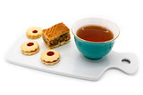 Cup of tea, a piece of apple pie and cookies with jam