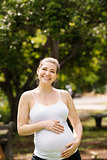 Portrait of happy and smiling pregnant woman in park