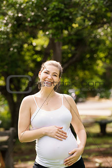 Portrait of happy and smiling pregnant woman in park