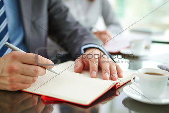 Hand with pen and notepad