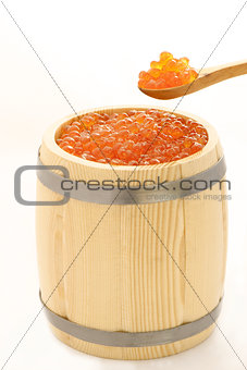 red salmon caviar in a wooden spoon and a barrel