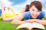 smiling pretty students lying on the grassland with books