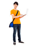 happy young student standing and using laptop