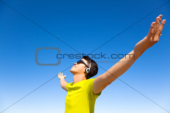 young man enjoying music  with blue sky background