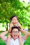 girl sitting father shoulder and make a funny facial expression