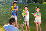 little guys using water guns to spray their father