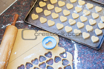 Wooden rolling pin, raw dough and heart shaped cookie cutter