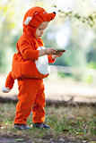 Toddler boy in fox costume holding smartphone