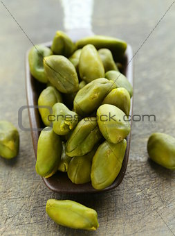 peeled green pistachio nuts on a wooden background