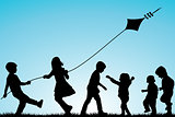 Group of children silhouettes with a kite outdoor