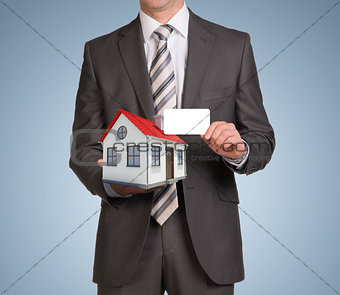 Businessman in suit hold empty card and small house