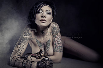  Beautiful woman with many tattoos posing indoors
