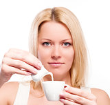 Woman pouring cream or milk into cup of coffee 