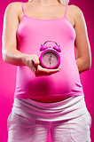 Pregnant woman holding alarm clock 