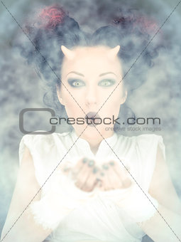 Portrait of devil woman blowing a white powder, conceptual photo