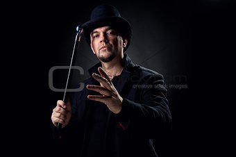 Handsome man wearing black hat and jacket holding stick